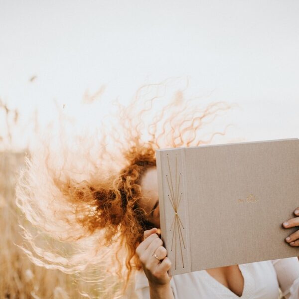 Kobieta tańczy z albumem beżowym na zdjęcia i macha włosami